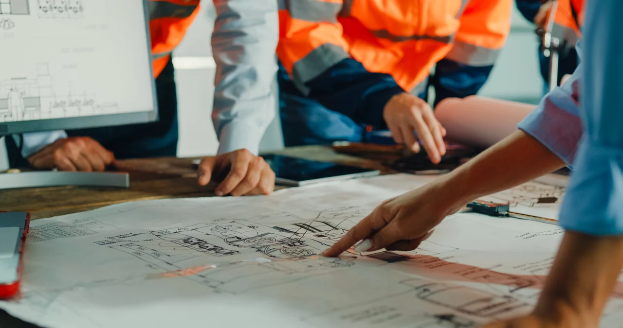 Industrial team reviewing mechanical drawings and a screen